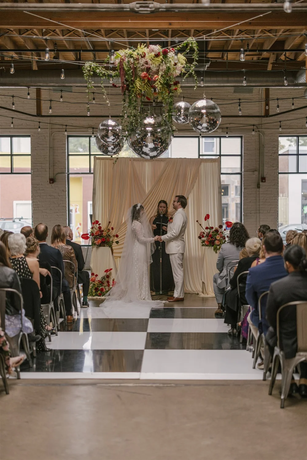 Wedding at SKYLIGHT with disco balls and greenery overhead, and a black and white dance floor