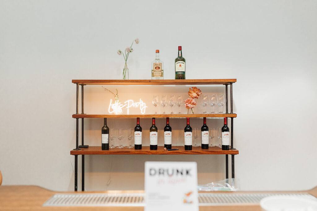 Bar set up for a wedding at THE 101 in Seattle with neon sign reading "let's party"