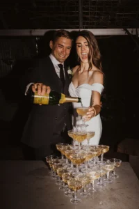 Bride and groom pouring "champagne" into a champagne glass tower