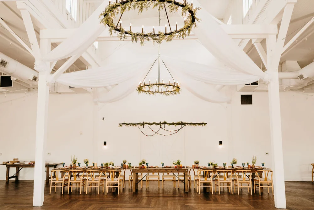Head table set up for a wedding with greenery hanging from the chandeliers and barn doors at Nashville Event planned by 828 Planning