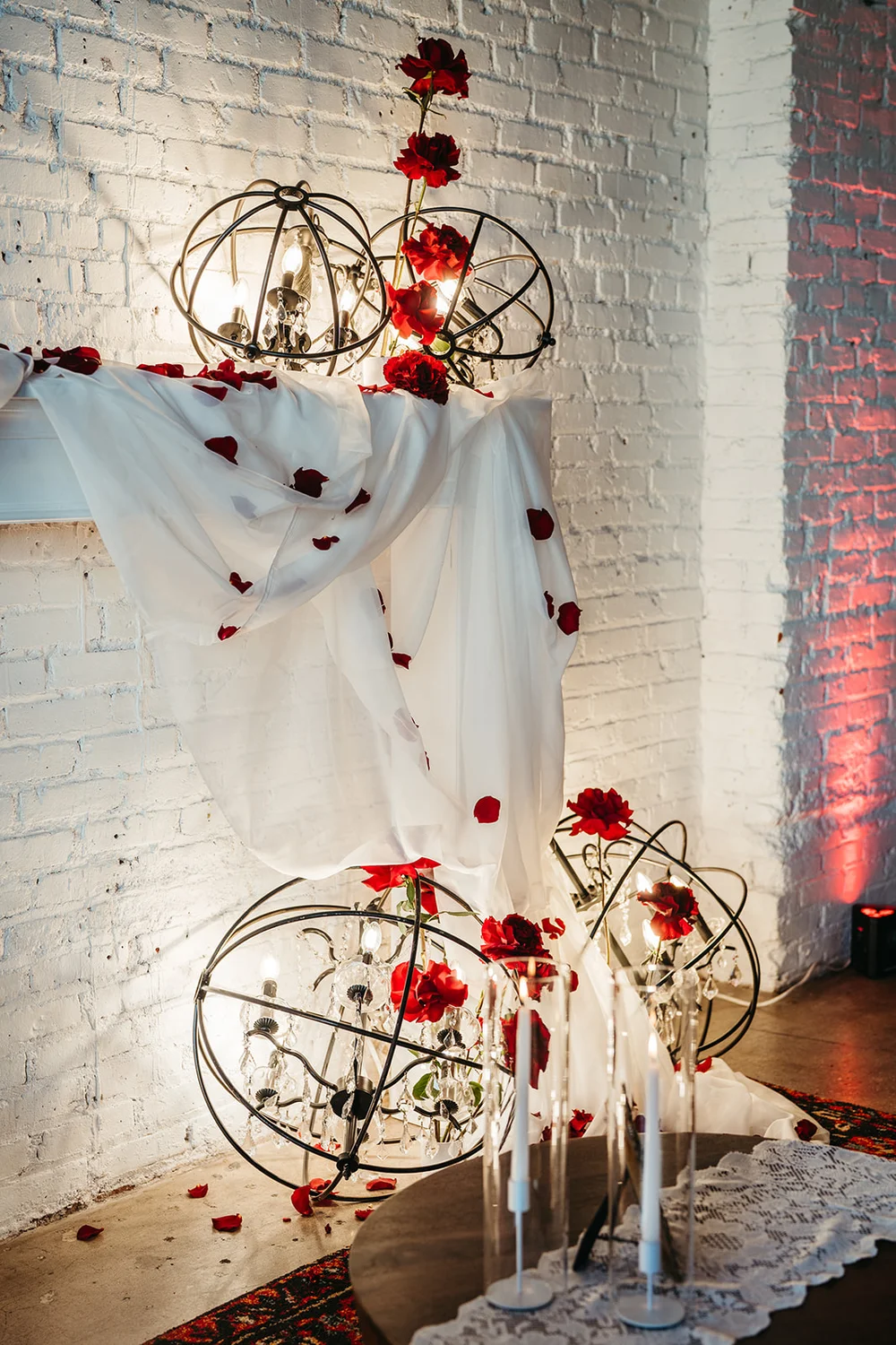 Faux fireplace at SKYLIGHT Denver decorated with red roses and white draping for a moody ’Til Death wedding open house by 828 Planning