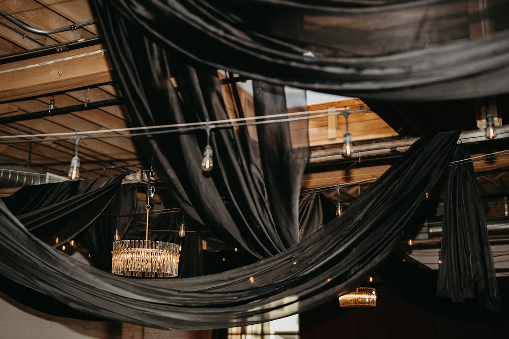 Black draping hanging from the ceiling at SKYLIGHT Denver for a moody ’Til Death wedding open house by 828 Planning