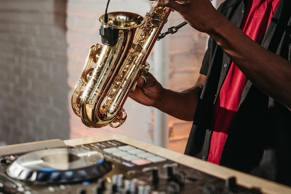Musician playing saxophone at DJ table during a moody wedding open house at SKYLIGHT Denver, produced by 828 Planning