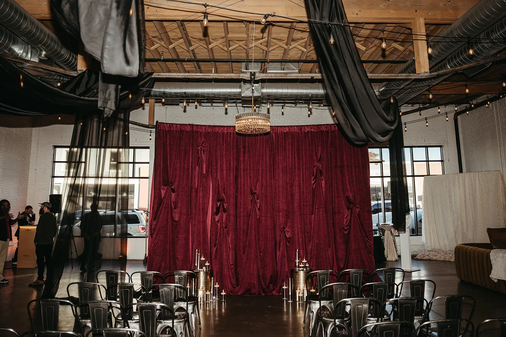 Wedding ceremony at SKYLIGHT Denver featuring moody decor and dramatic draping by 828 Planning