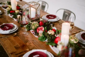 Holiday tablescape with white chargers and red plates, pomegranates and fruit and candles as the centerpiece